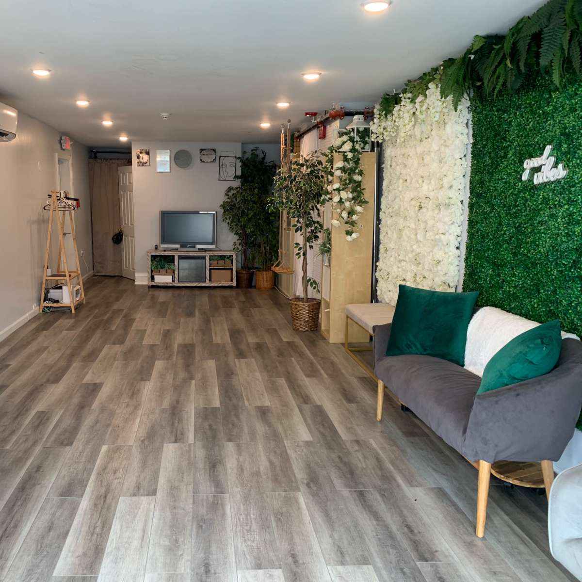 A modern interior space with a green wall feature, a seating area, a small dining table, and various decorative elements.