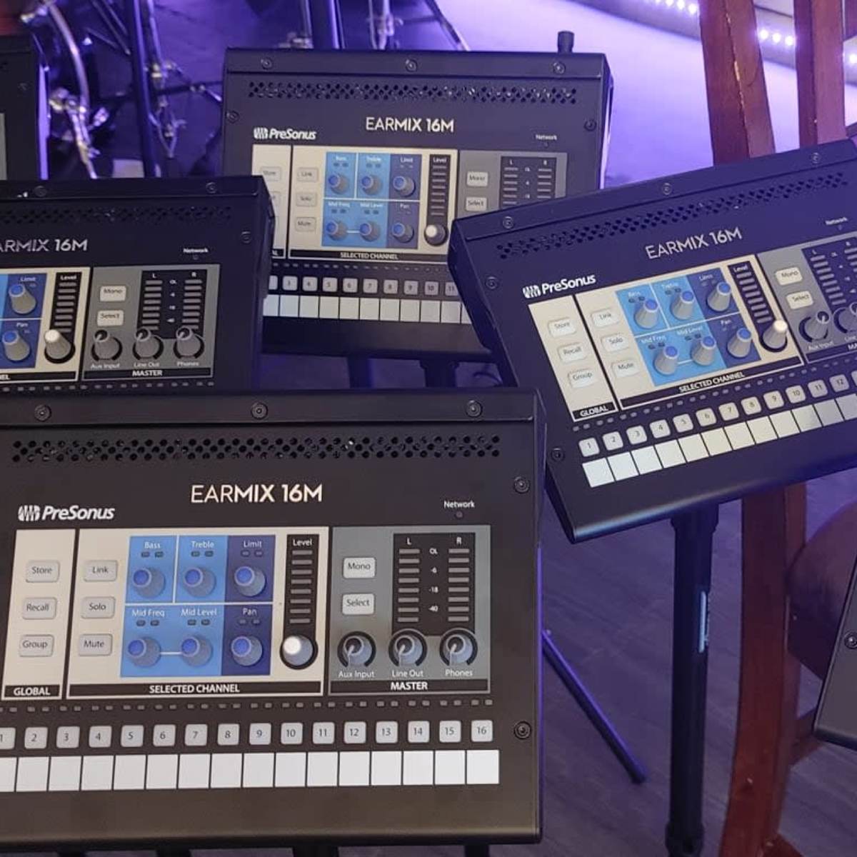 Several PreSonus EarMix 16M devices arranged on a surface in a music studio setting.