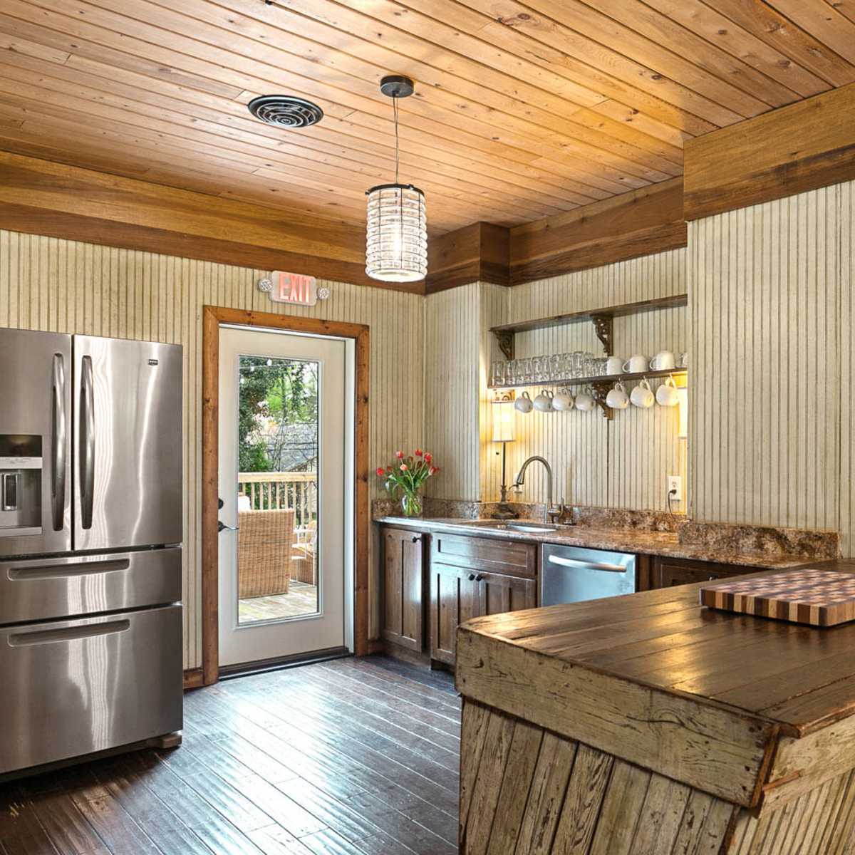 The kitchen features stainless steel appliances, wooden accents, and a bar counter with a cutting board.