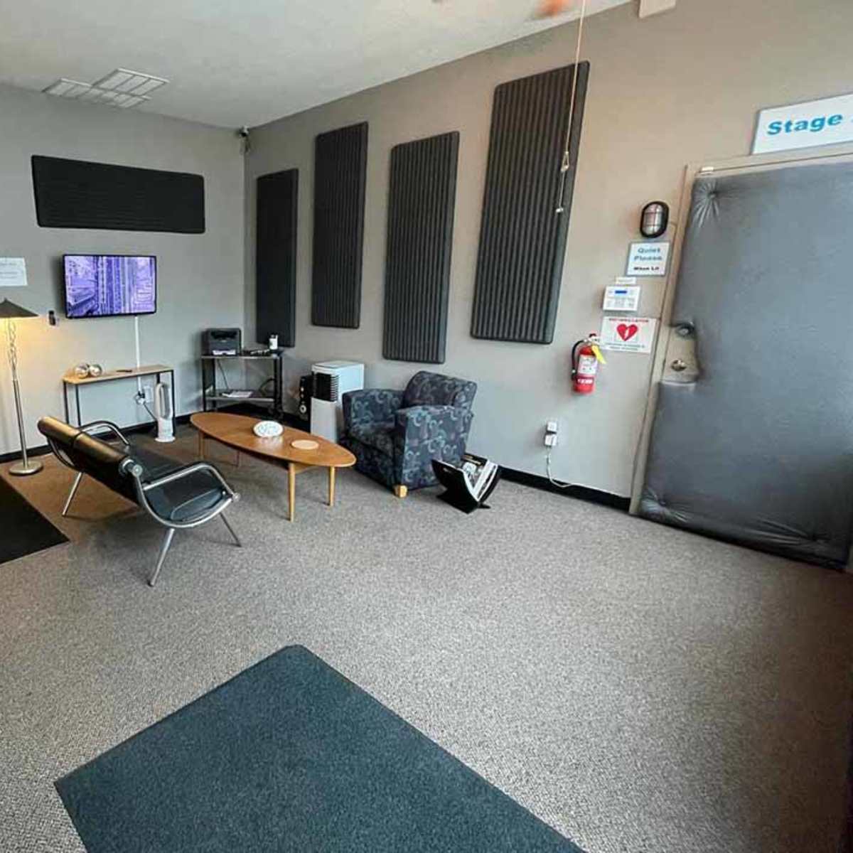 A small waiting room with a chair, a modern table, and access to a room in the background.