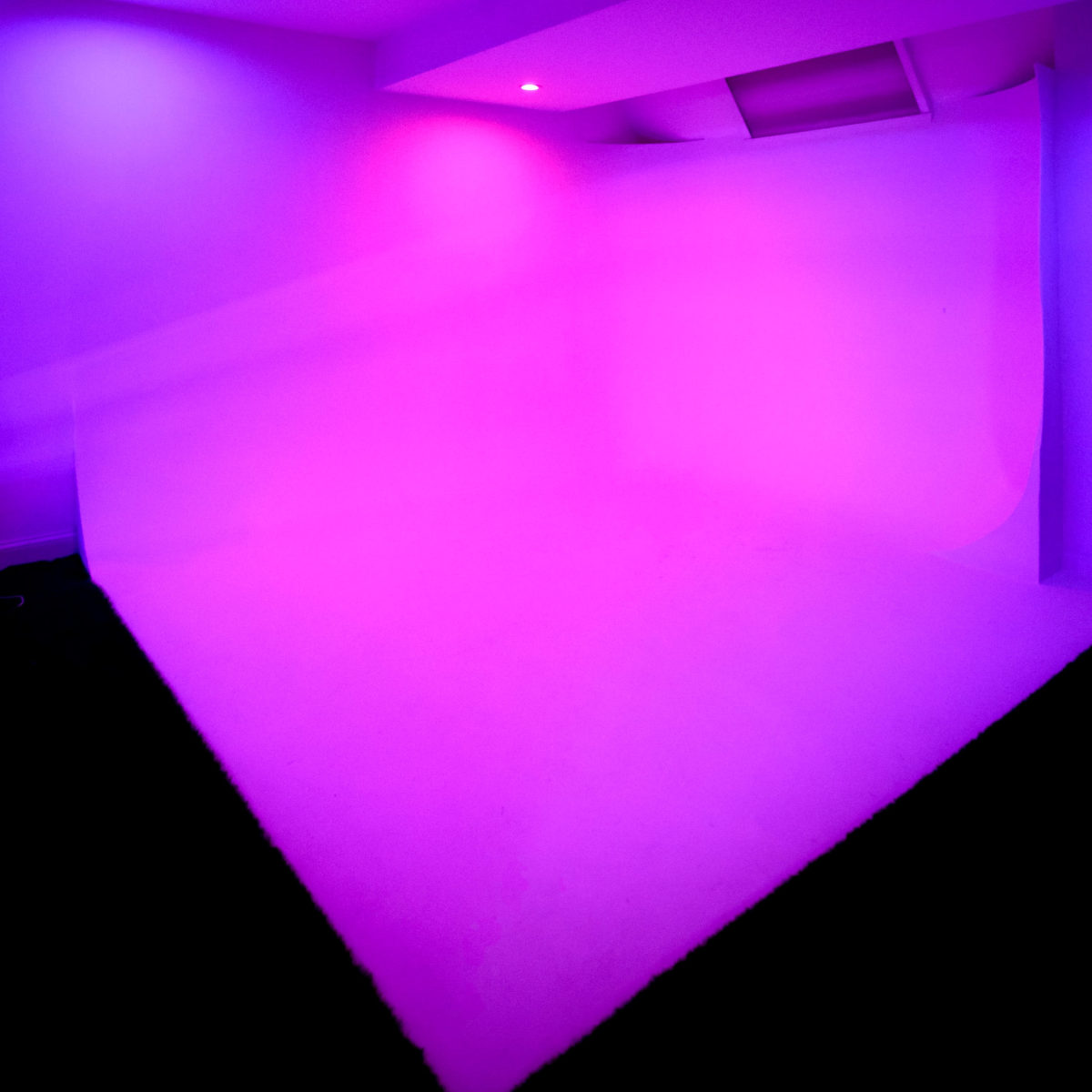 A room with a gradient of purple lighting illuminating the walls and floor.