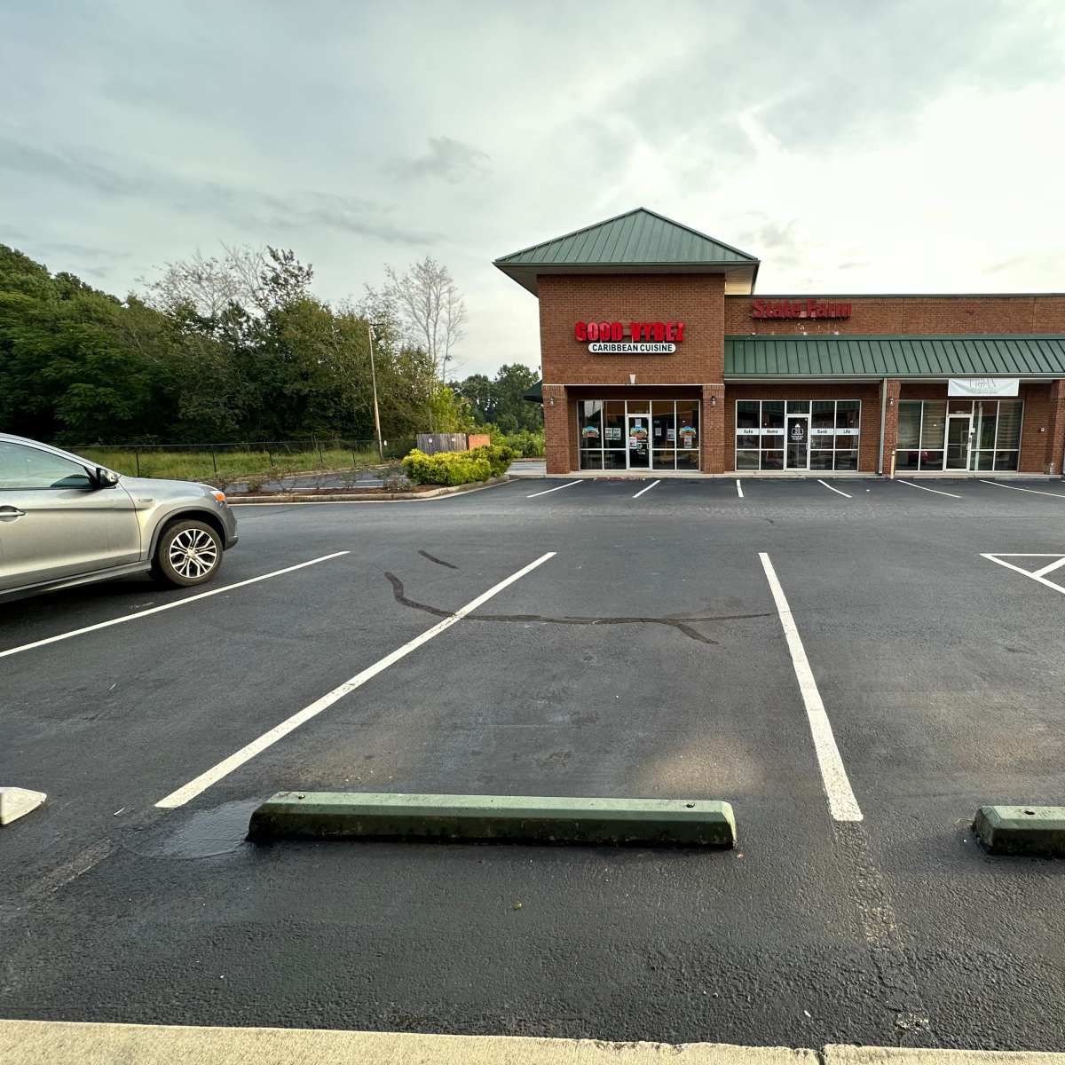 A nearly empty parking lot adjacent to a commercial building with several storefronts.