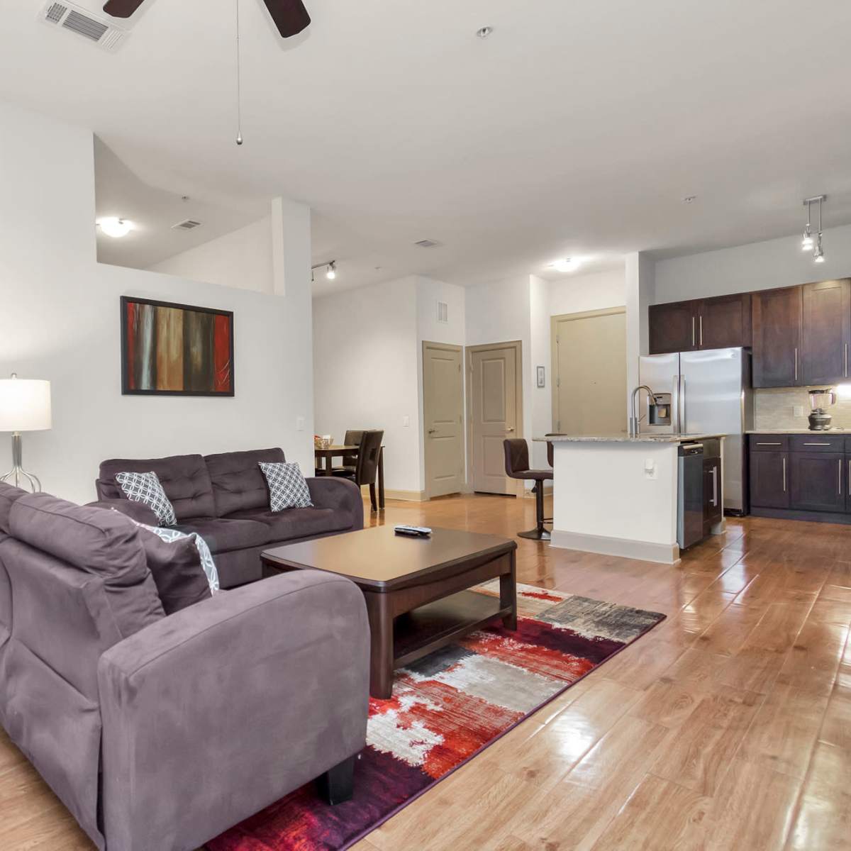 A living room with two couches, a coffee table, and a nearby kitchen area visible in a modern apartment.