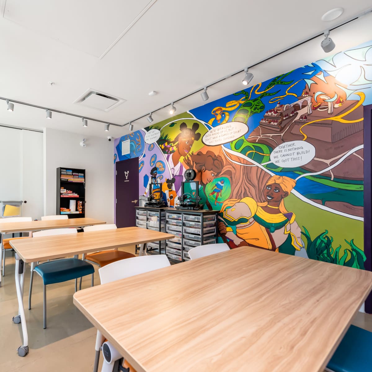 A brightly colored classroom featuring multiple wooden tables and a mural depicting characters and scenes on one wall.