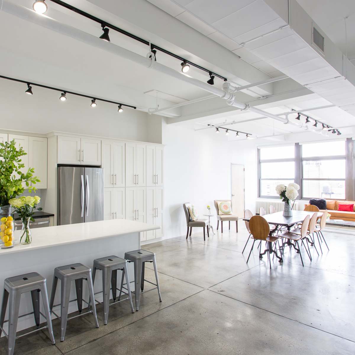 A modern open-concept kitchen and dining area with a large island, stainless steel appliances, and a dining table surrounded by chairs.