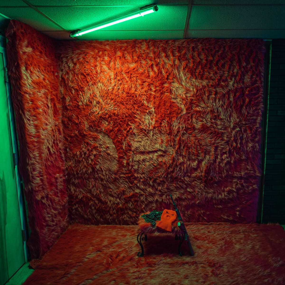 The scene features a room with a bright red fuzzy wall covering, a matching floor, and a small black metal table topped with an orange object.