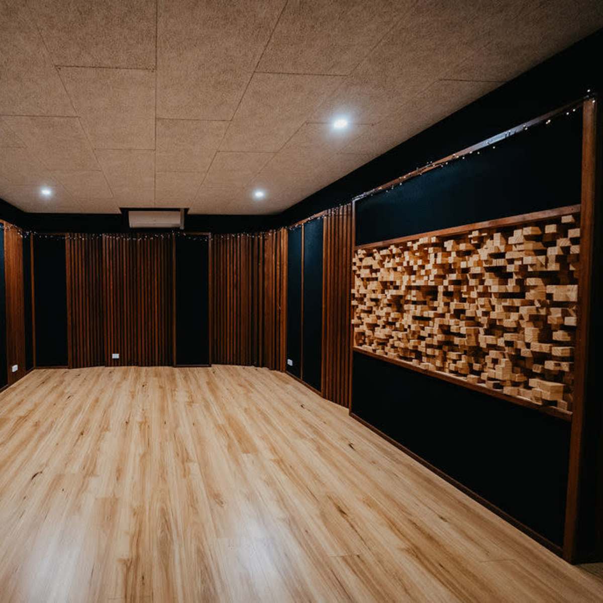 A soundproof recording studio with wooden paneling, a light wooden floor, and acoustic treatment on the walls.