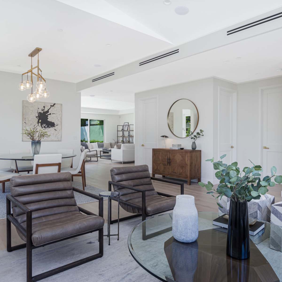 A modern living area features sleek furniture, a round coffee table, and large windows allowing natural light.