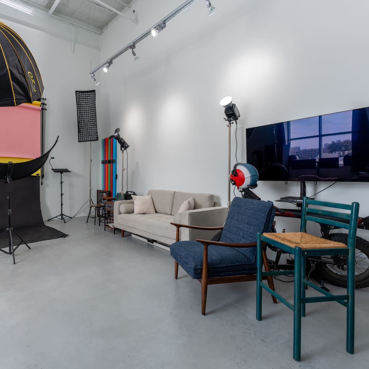 A photography studio with a colorful backdrop, a couch, chairs, and various lighting equipment.
