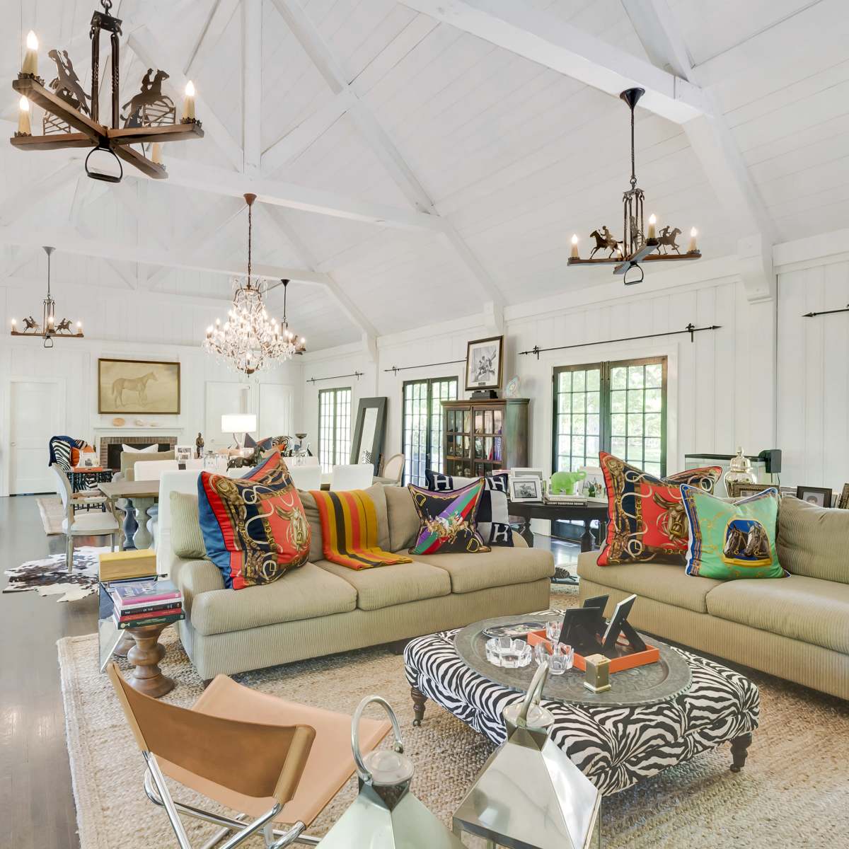 The living area features a spacious design with high ceilings, multiple seating arrangements, and a mixture of decorative lighting fixtures.