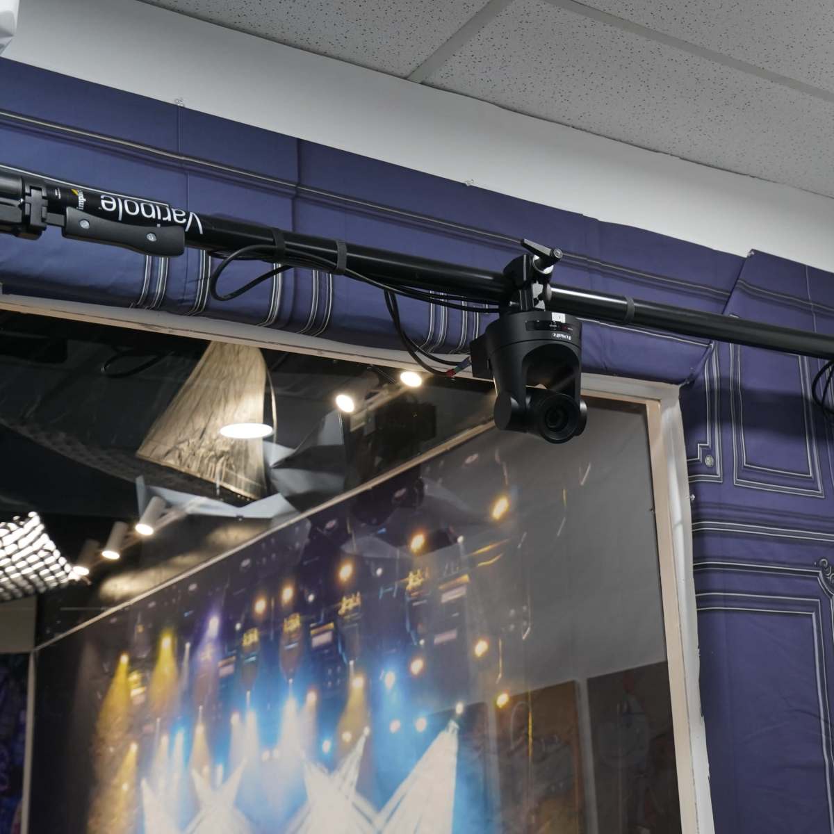 A lighting rig mounted on a ceiling near a wall with textured blue wallpaper, featuring multiple spotlights aimed downwards.