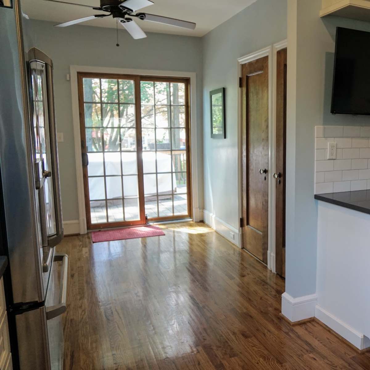 A kitchen with stainless steel appliances, white cabinetry, and a door leading to a porch, illuminated by natural light.