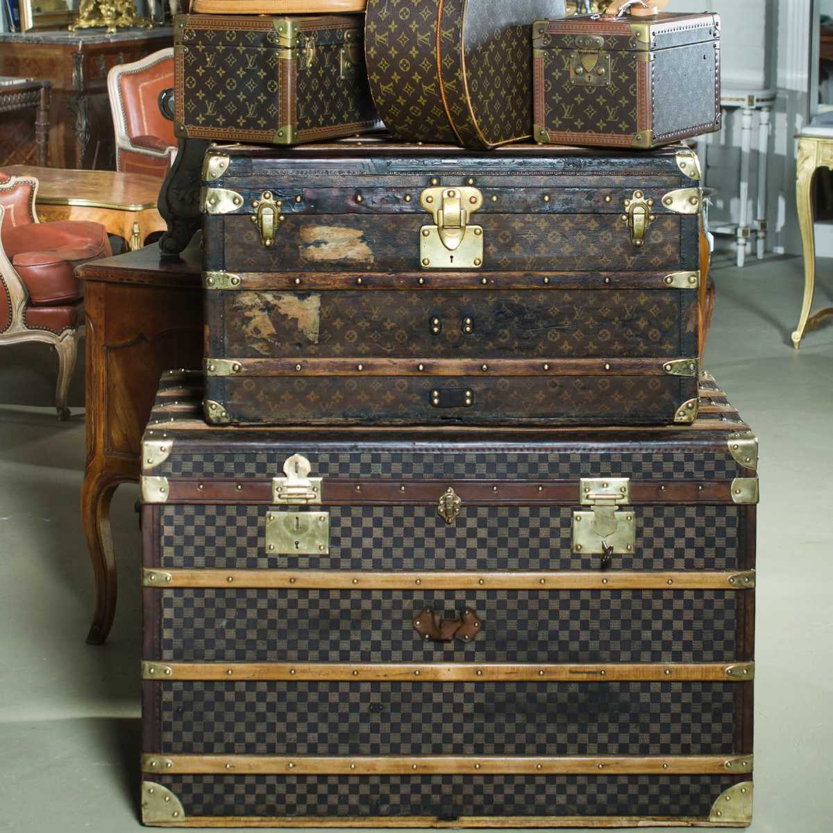 A stack of vintage Louis Vuitton suitcases and trunks placed in a well-decorated interior space.