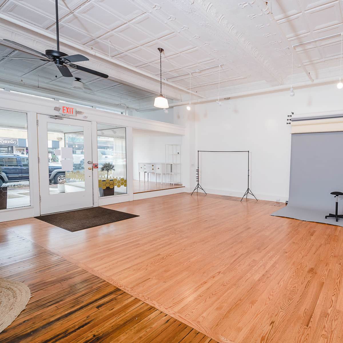 A spacious indoor photography studio featuring a gray backdrop, wooden floors, and a blue couch.