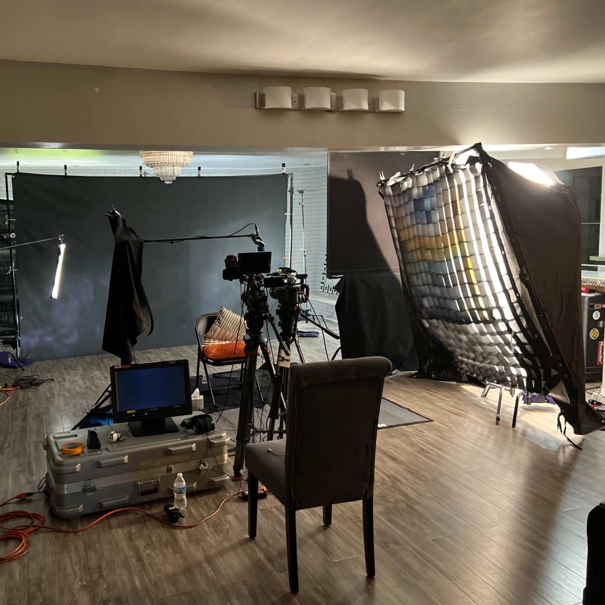 A film setup showcases a camera, lighting equipment, and a backdrop in a spacious living area.