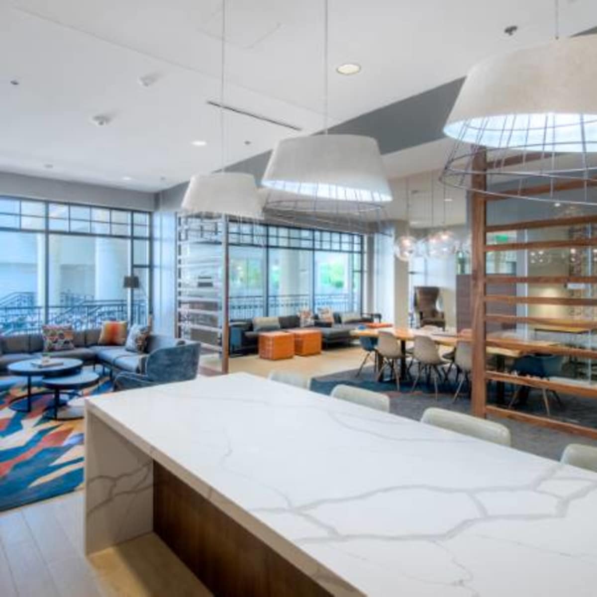 A modern communal lounge area with a large countertop, pendant lighting, and various seating arrangements.
