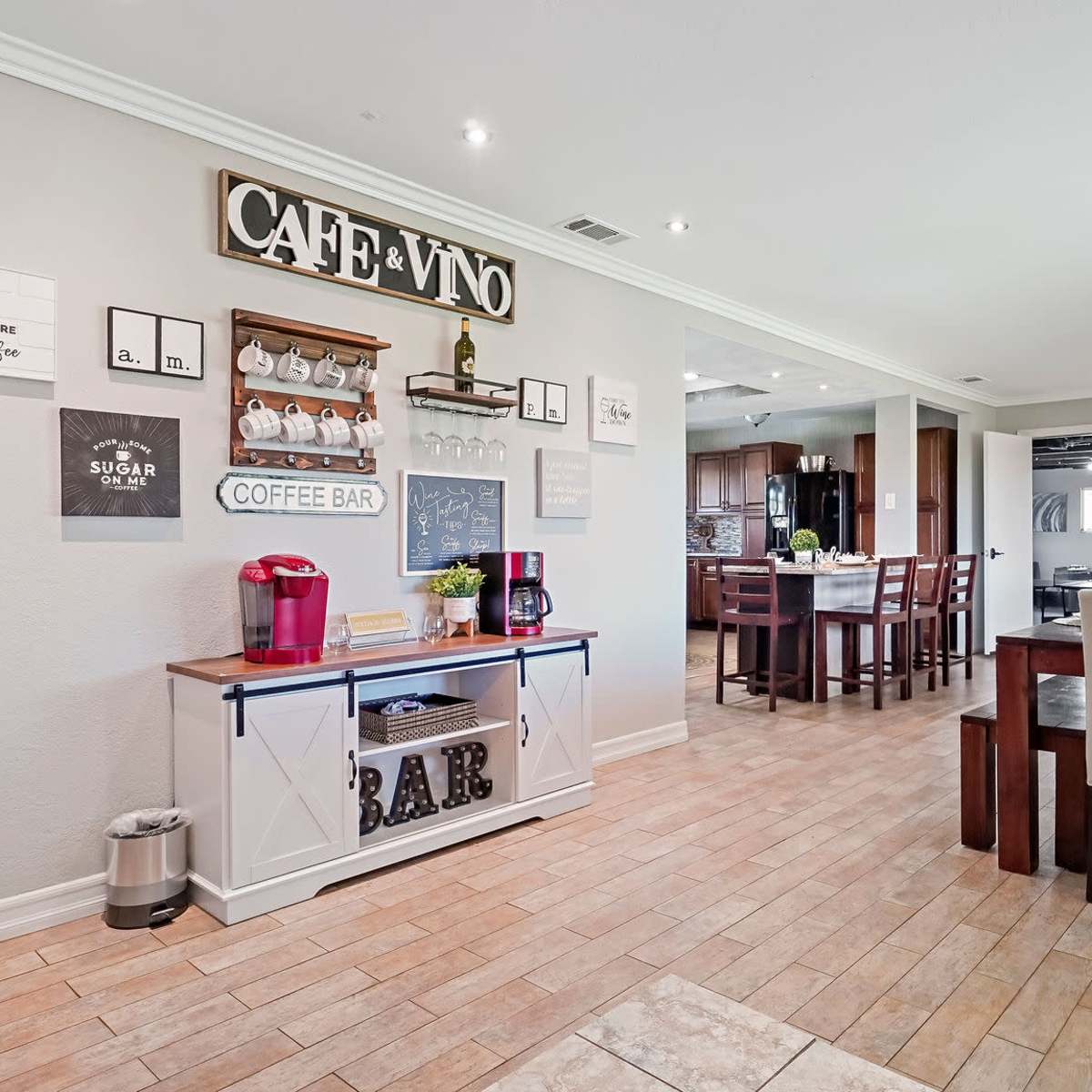 A spacious dining area features a coffee bar, a dining table with chairs, and a well-decorated wall showcasing various signs and shelving.