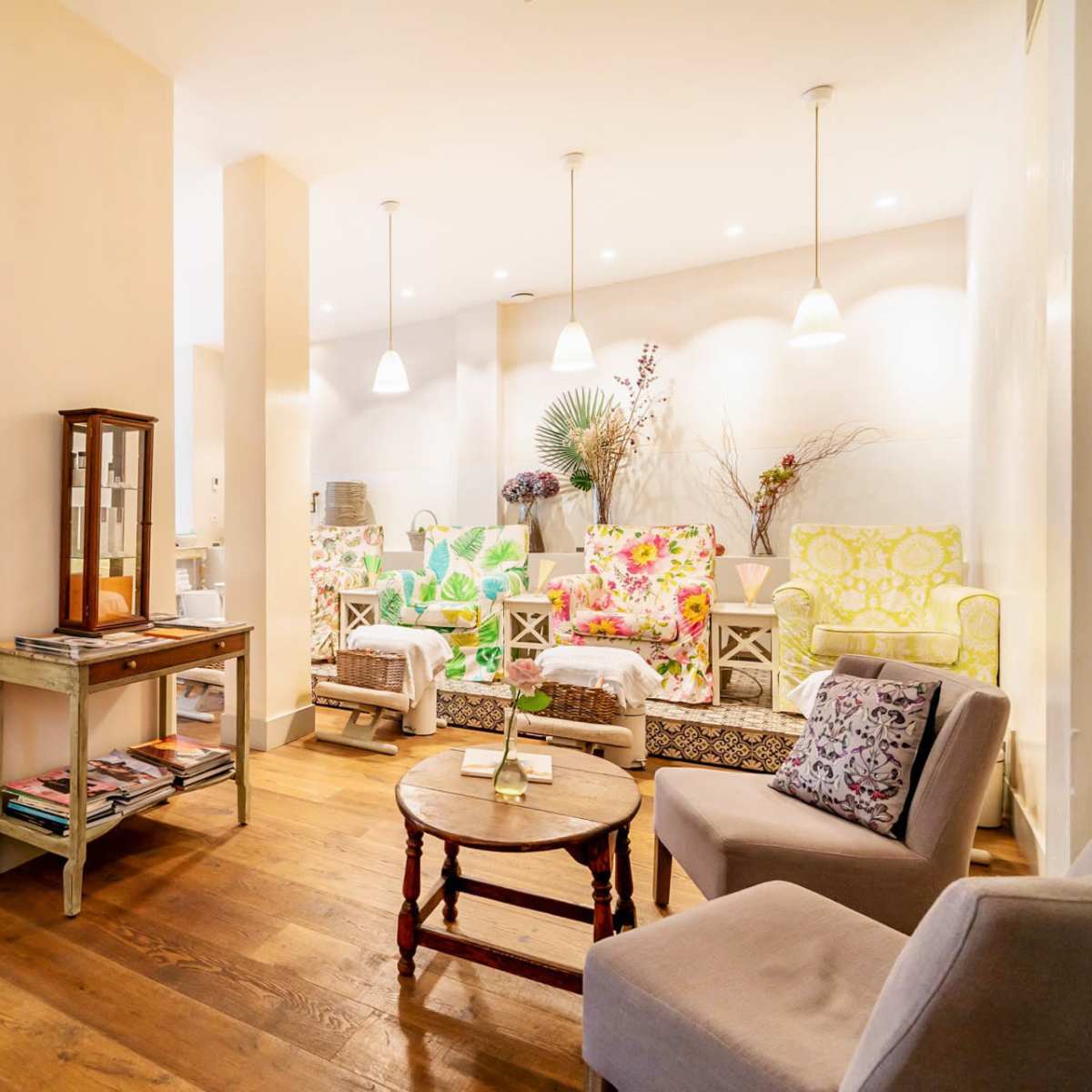 A bright and inviting café features colorful upholstered seating, light wooden floors, and a mix of tables and chairs arranged for dining.