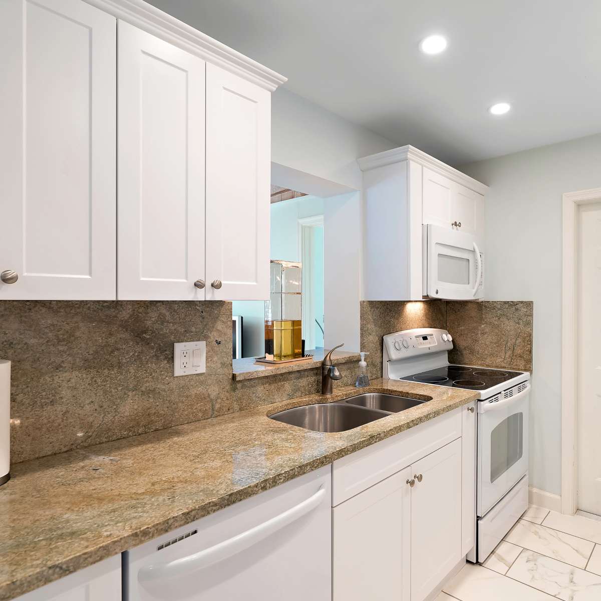 A modern kitchen featuring white cabinetry, granite countertops, and stainless steel appliances.