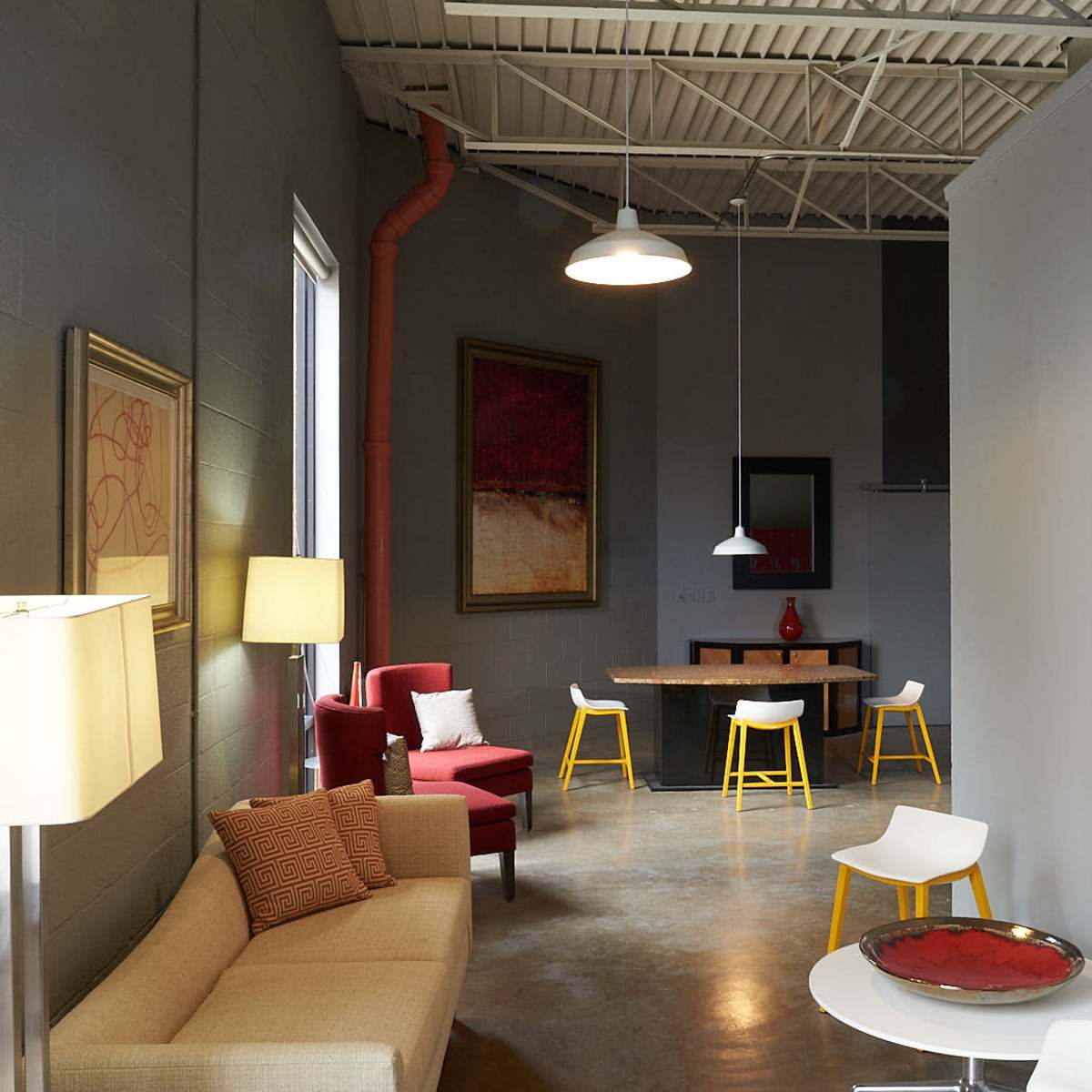 A modern, open interior space featuring a sofa, armchairs, a dining table, and various lighting fixtures.
