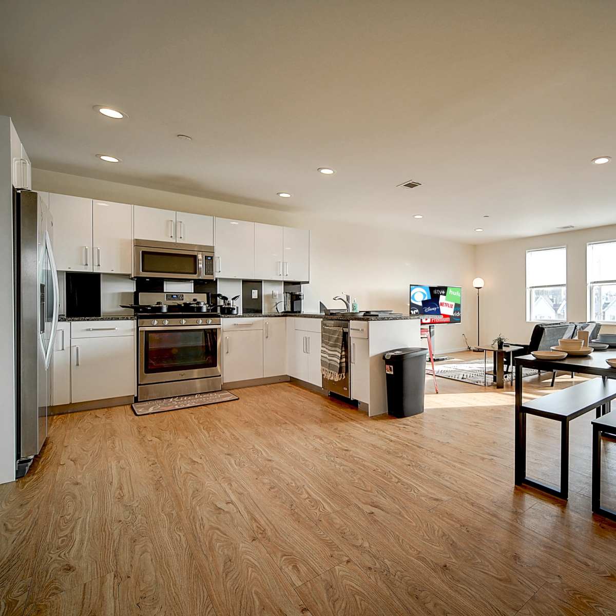 A modern, open-concept kitchen and living area with a dining table and large windows allowing natural light.