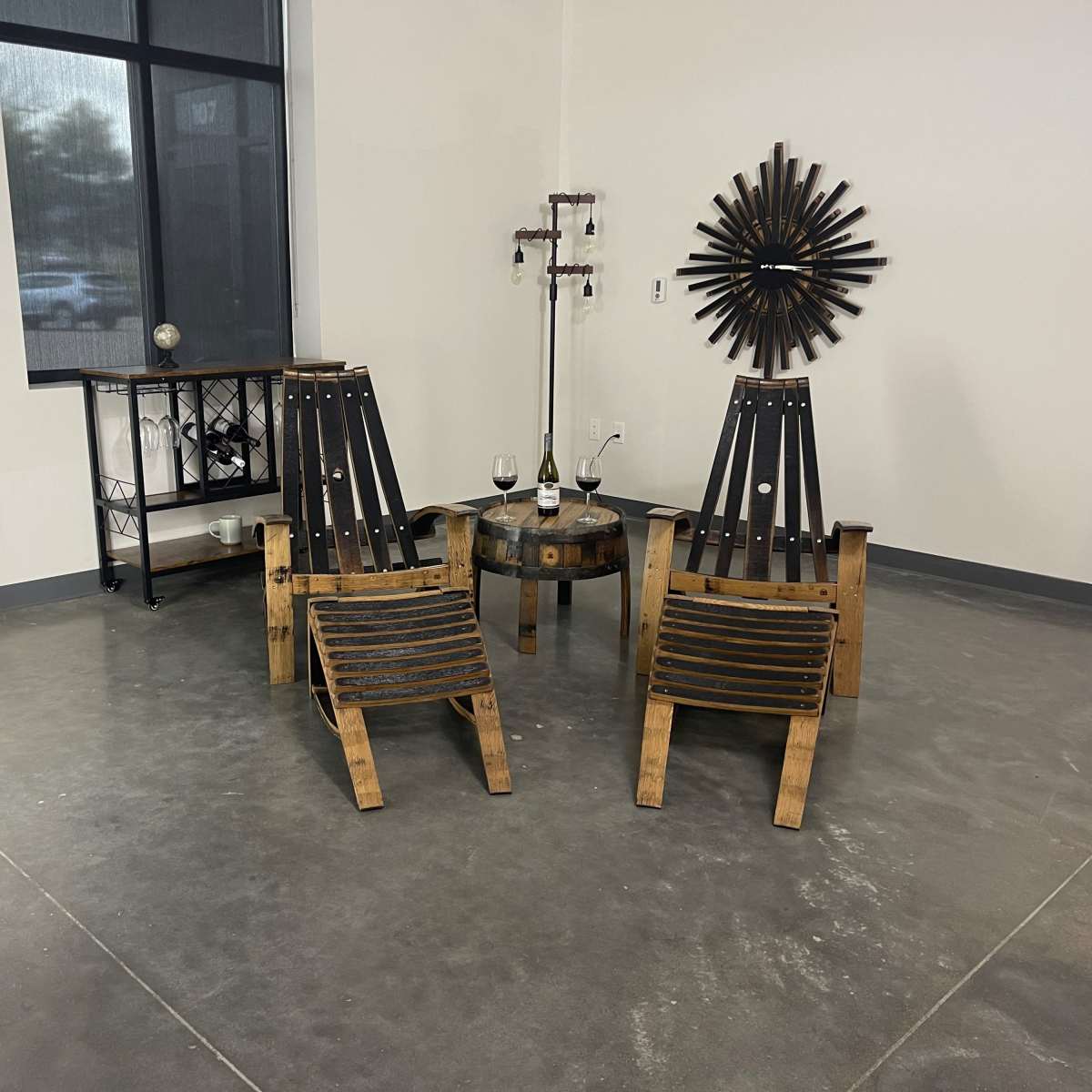A modern interior space with two wooden lounge chairs positioned around a circular table, accompanied by two glasses of wine.