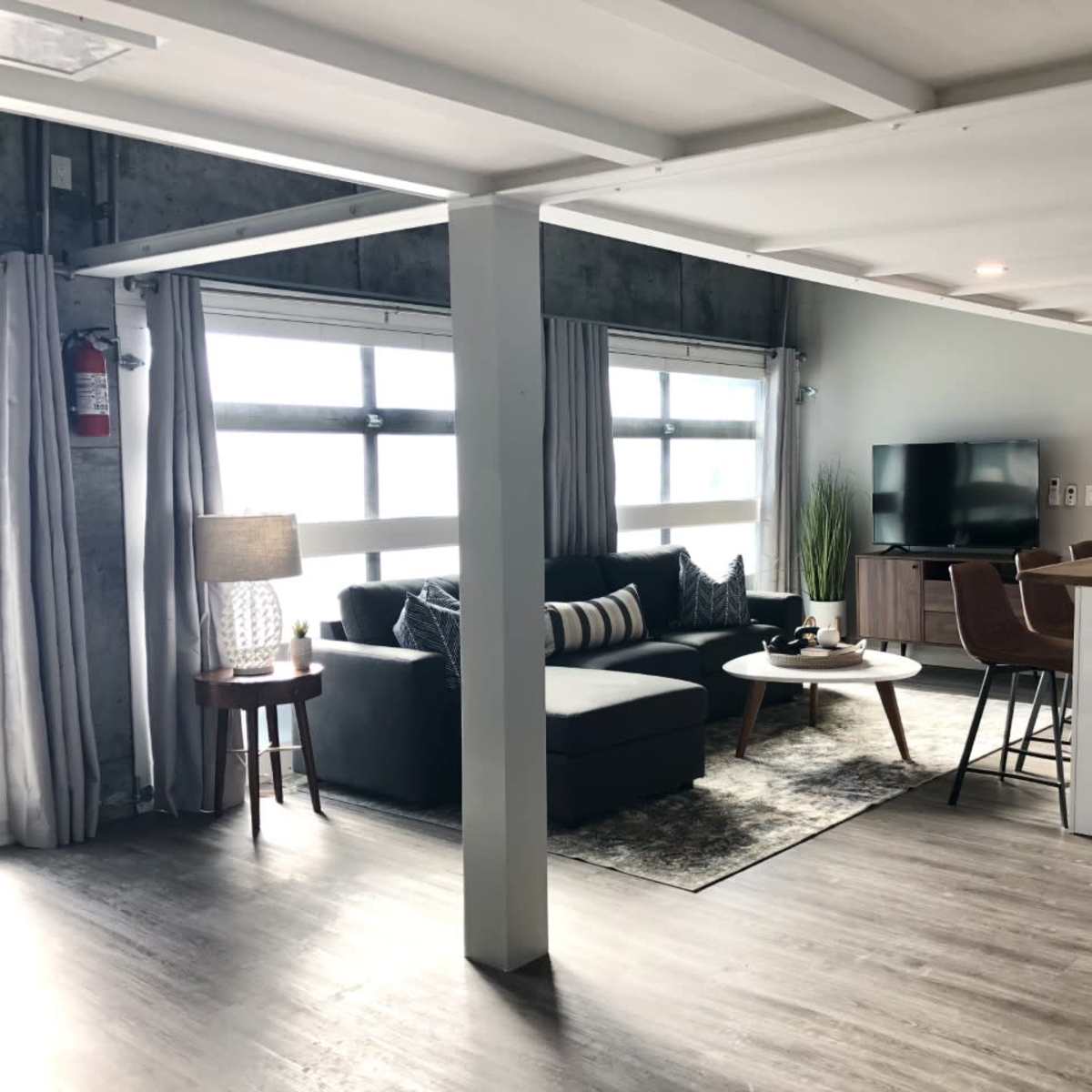 A modern open-concept living space featuring a sofa, coffee table, television, and kitchen island with seating.