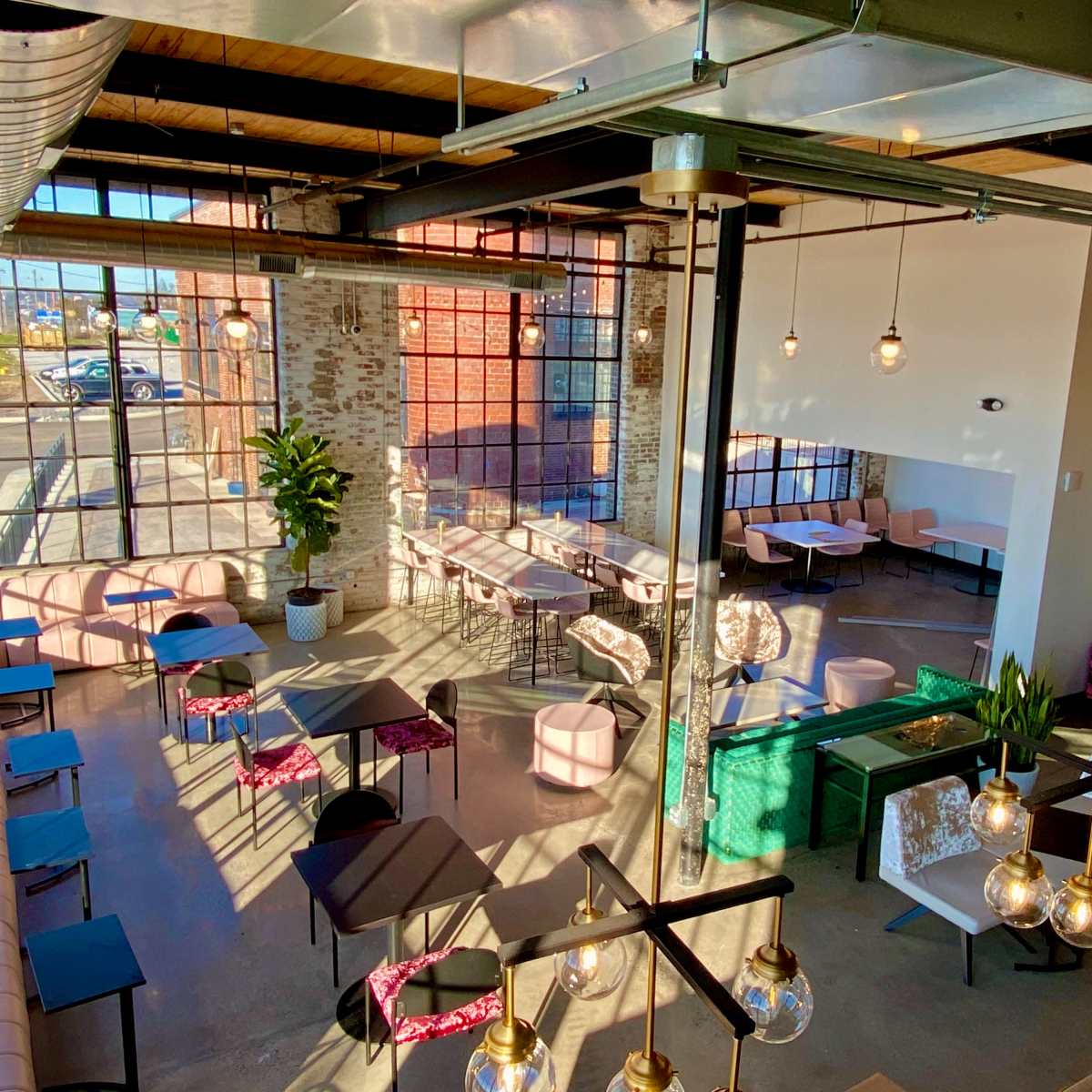 A spacious cafe with large windows, modern furniture, and various seating arrangements.