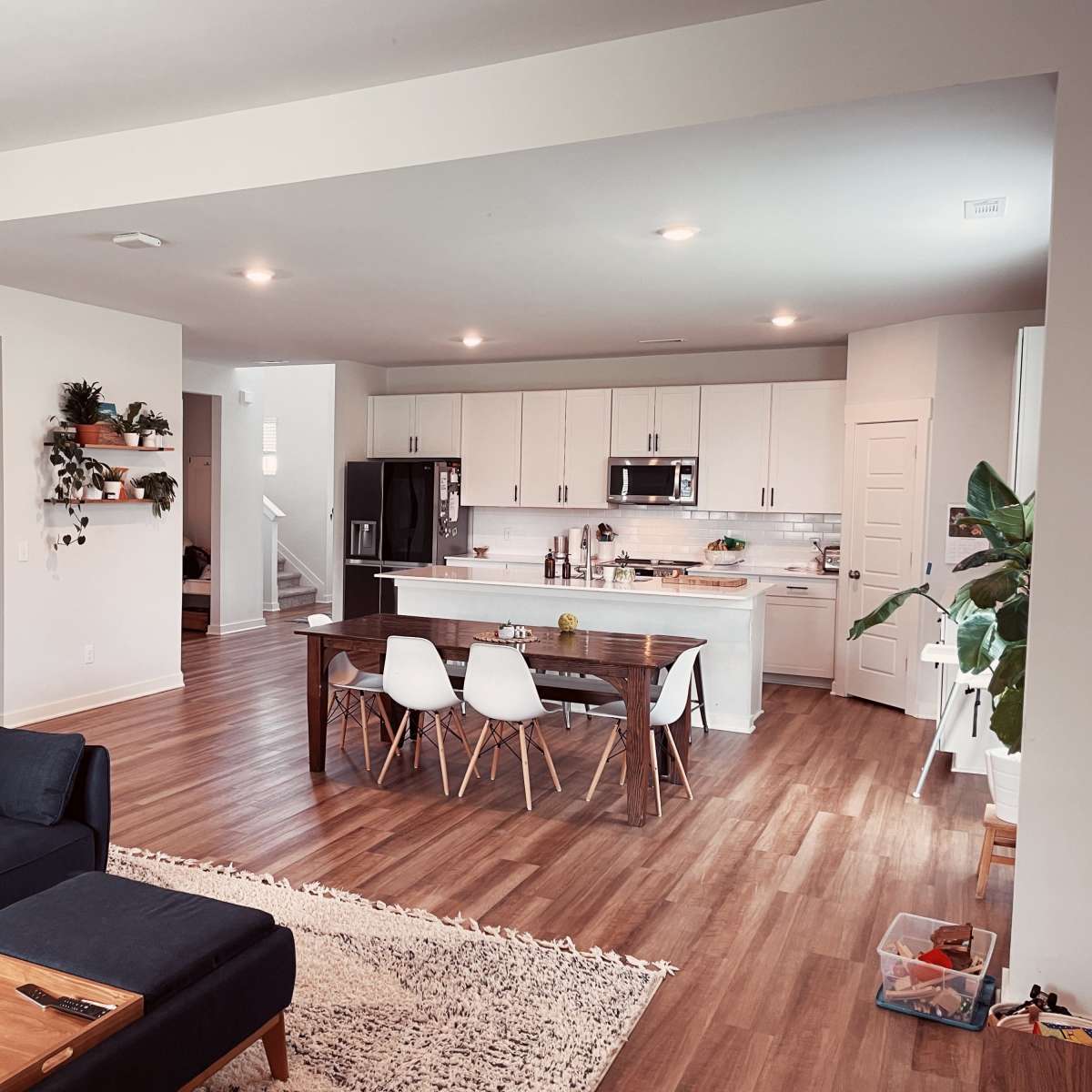 A modern open-concept living space features a kitchen with white cabinets, a dining table, and a cozy seating area.
