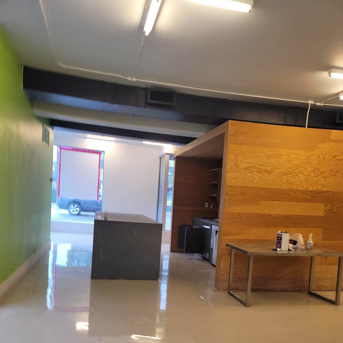 An interior space with green and wood-paneled walls, a grey countertop, and a stainless steel table.