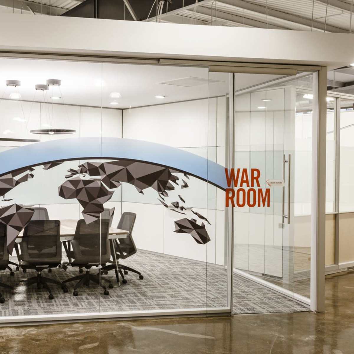 A modern conference room with a glass wall featuring a world map design and the words "WAR ROOM" prominently displayed.