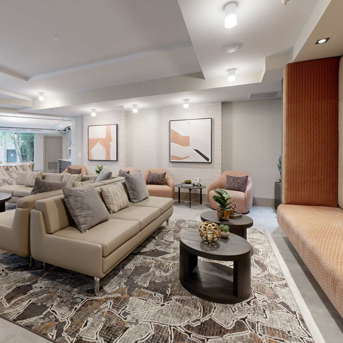 A modern lounge area with beige sofas, round tables, and decorative artwork on the walls.