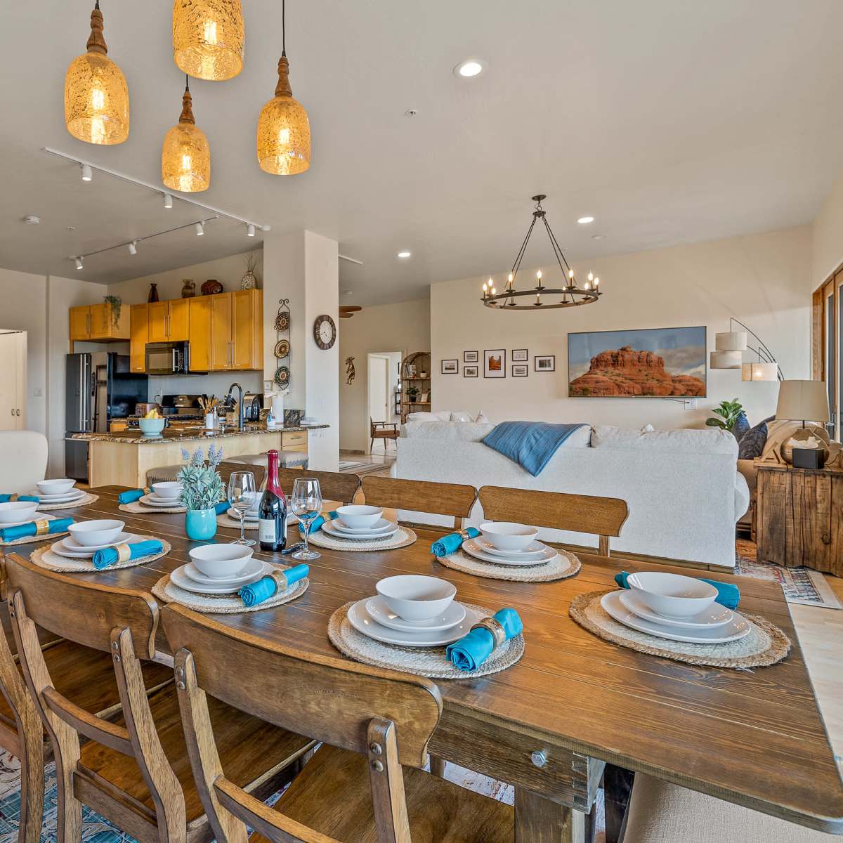 A dining table is set with plates and utensils, and a kitchen area is visible in the background with yellow cabinets and a living space featuring a couch and decorative items.