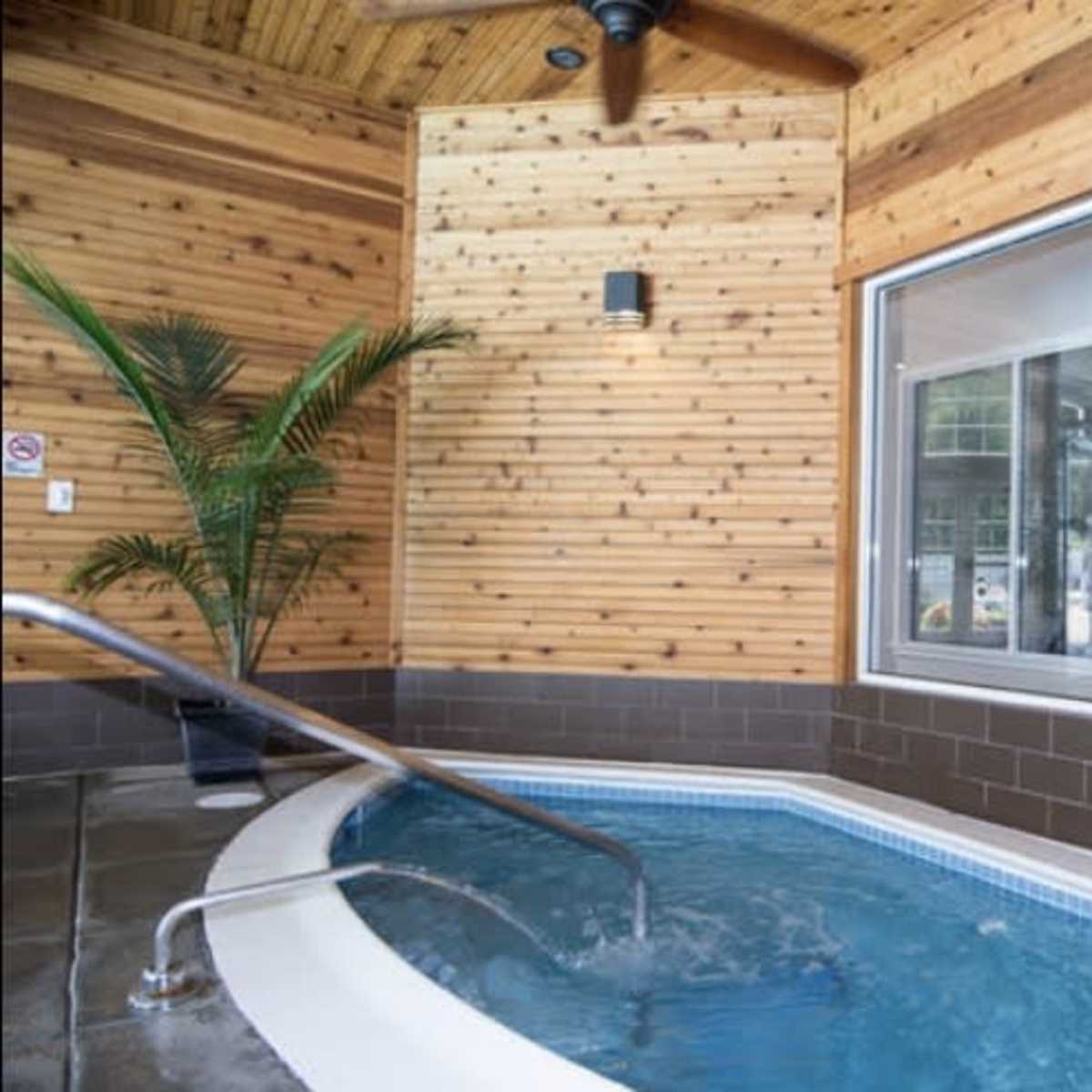 A small indoor spa area with a circular hot tub, wooden walls, and a large window.