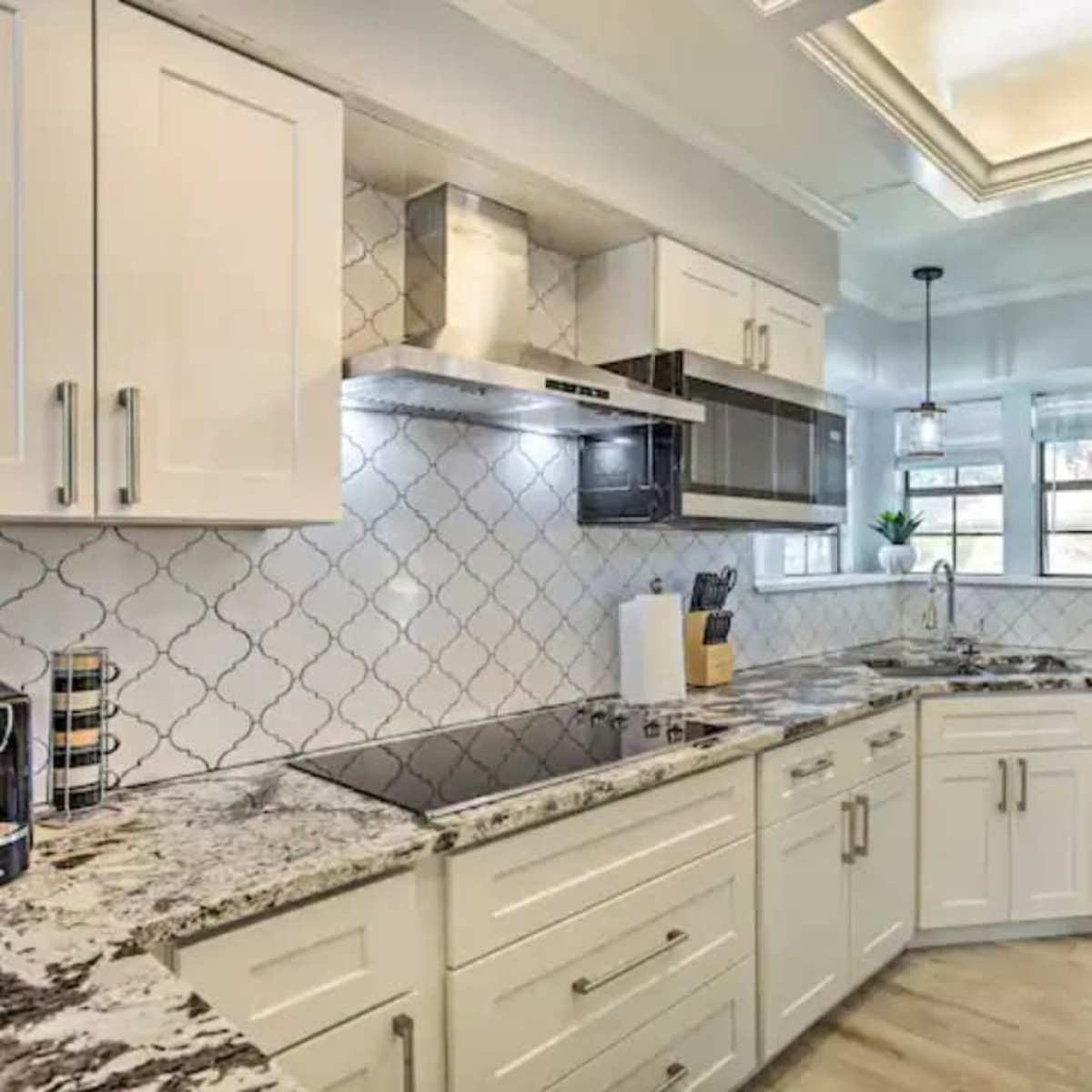 A modern kitchen with white cabinetry, a granite countertop, and stainless steel appliances.