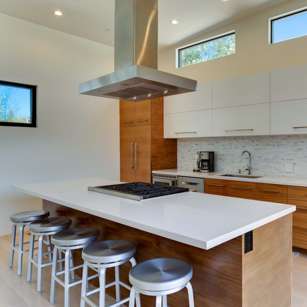 A modern kitchen with a central island, stainless steel appliances, and wooden cabinetry.