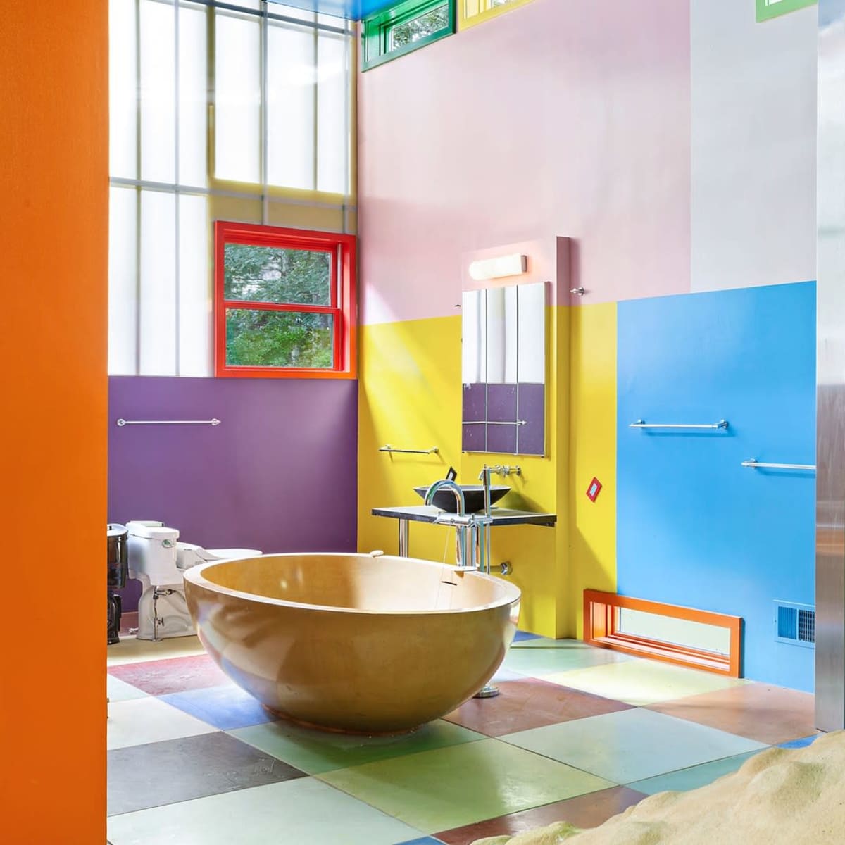 A colorful bathroom featuring a rounded bathtub, vibrant walls in assorted shades, and a modern sink area.