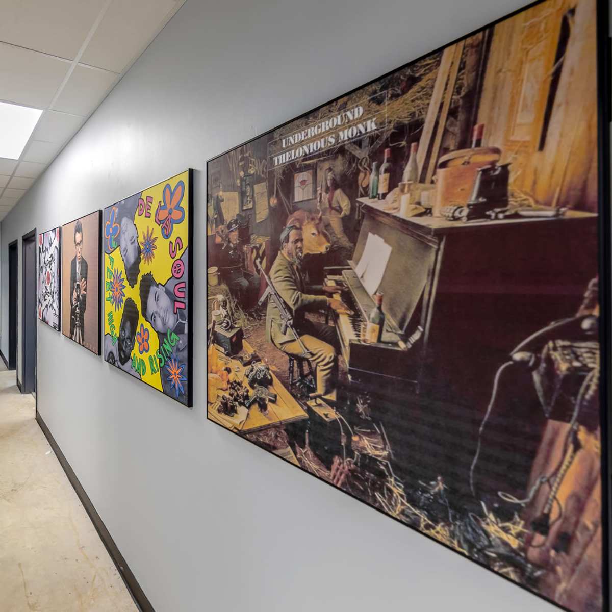 A long hallway is lined with colorful artwork and photographs on the walls, leading to several doorways.