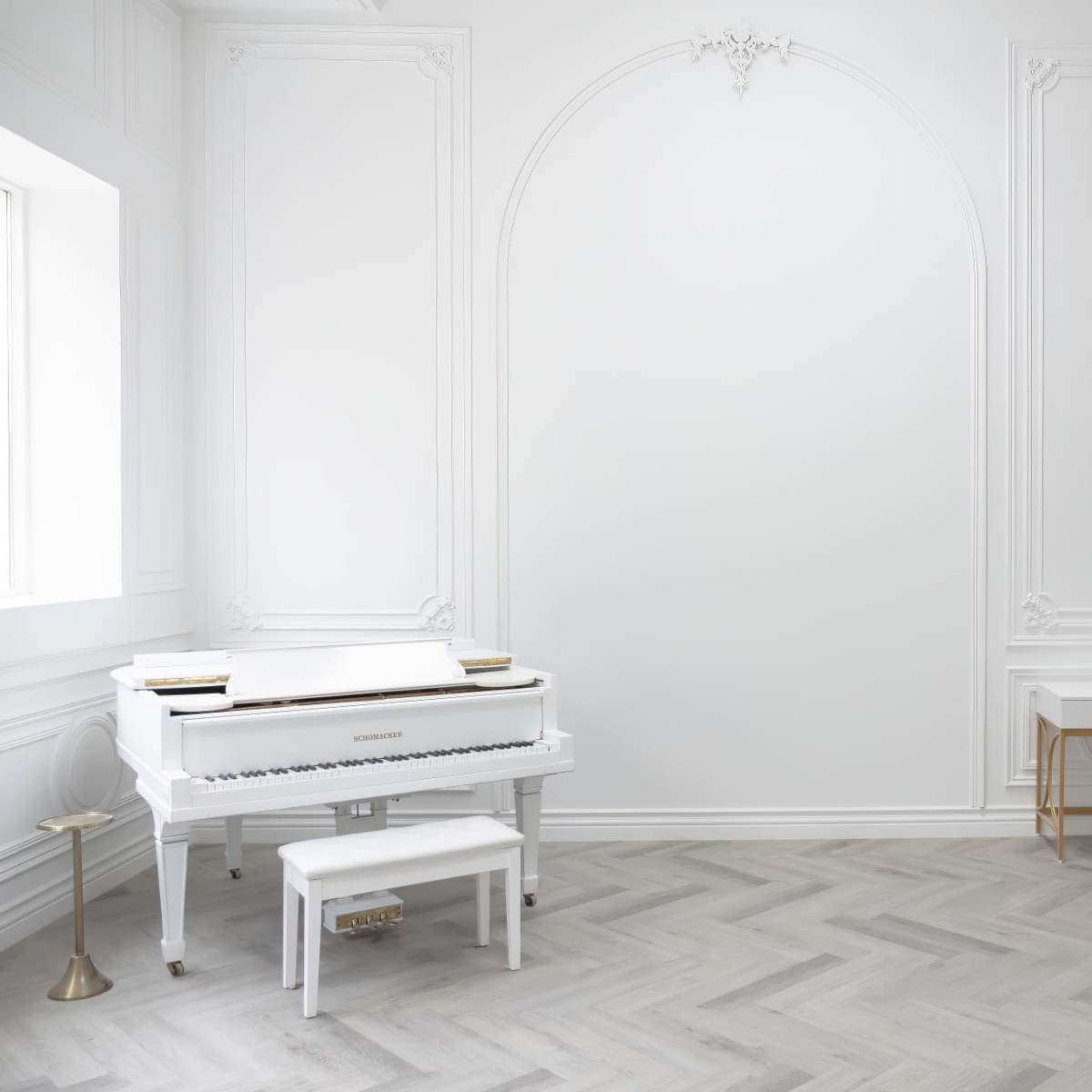 The room features a white grand piano, a modern desk, and a cream-colored chair against a light-colored, intricately designed wall.