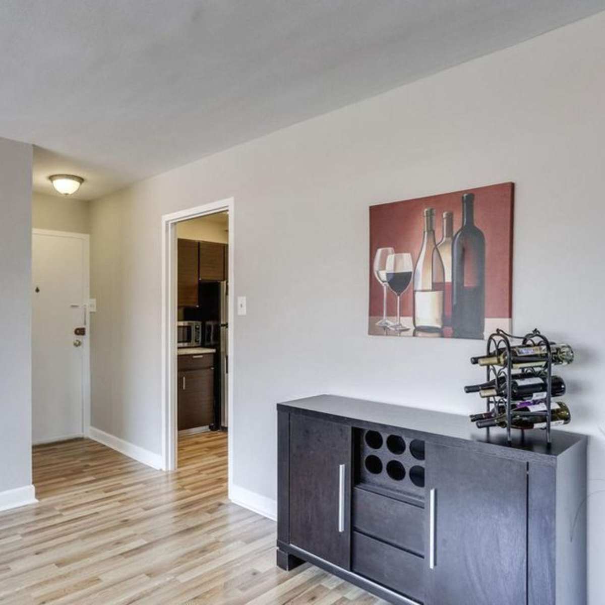 A living room with a gray sofa, a wine rack, and a wall decoration featuring wine bottles and glasses.