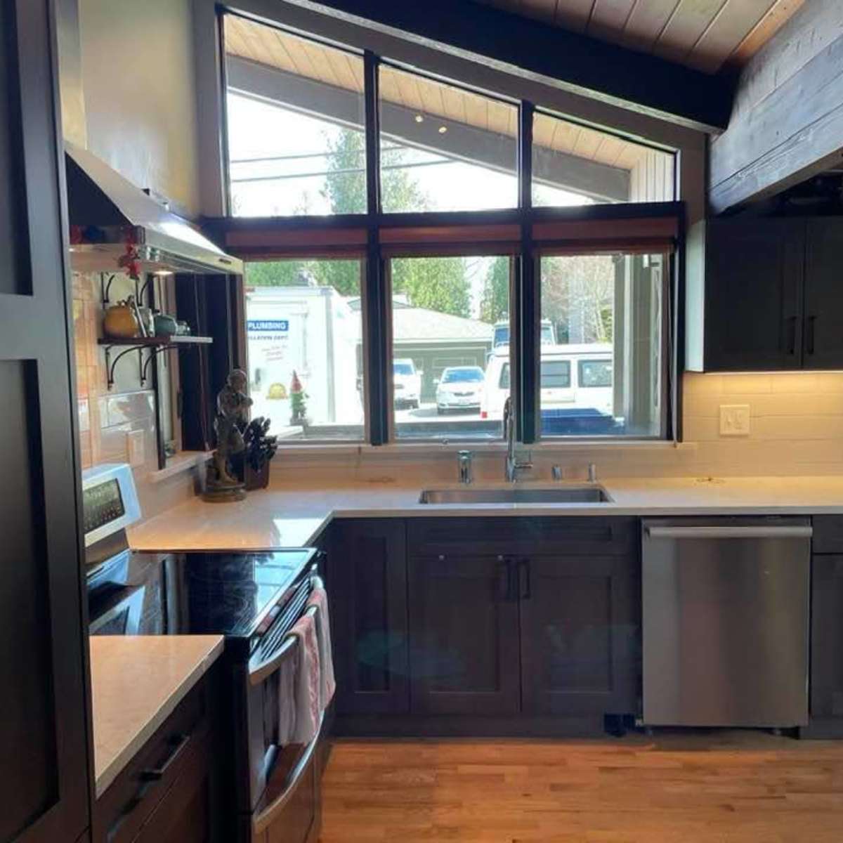 A kitchen with dark cabinetry, a window providing natural light, and modern appliances.