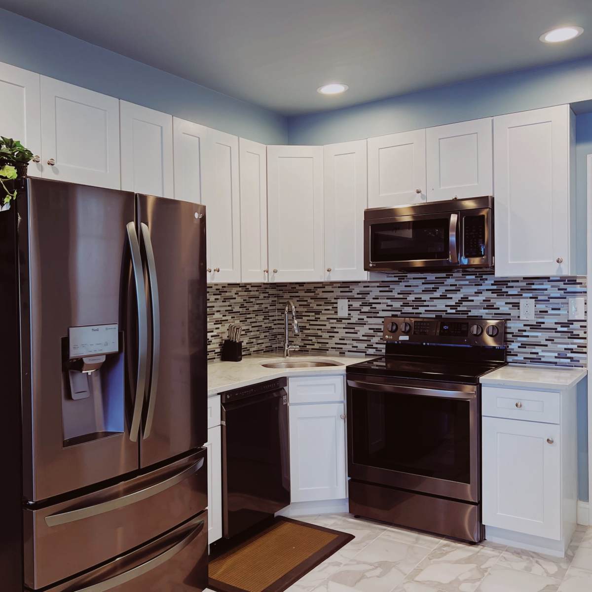 A modern kitchen featuring stainless steel appliances, white cabinetry, and a tiled backsplash.