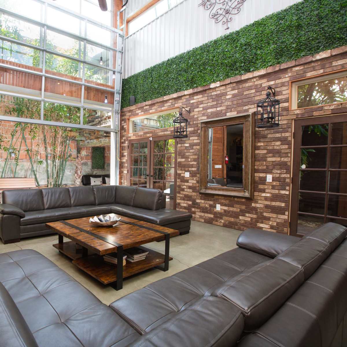 A spacious living area with a large sectional sofa, a coffee table in the center, and large windows allowing natural light to fill the room.