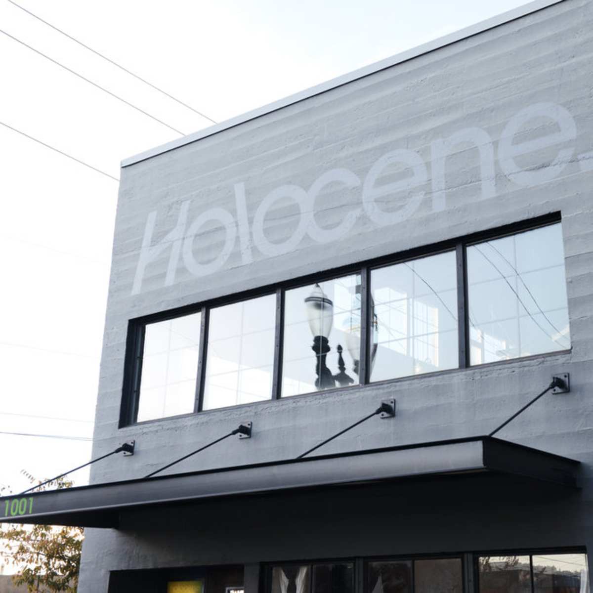The exterior of a building displays the word "Holocene" in large, faded lettering above its windows.