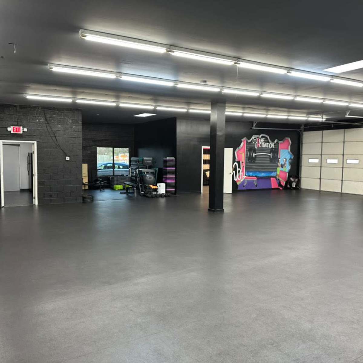 A spacious, empty room with polished black flooring and large garage doors on one side.