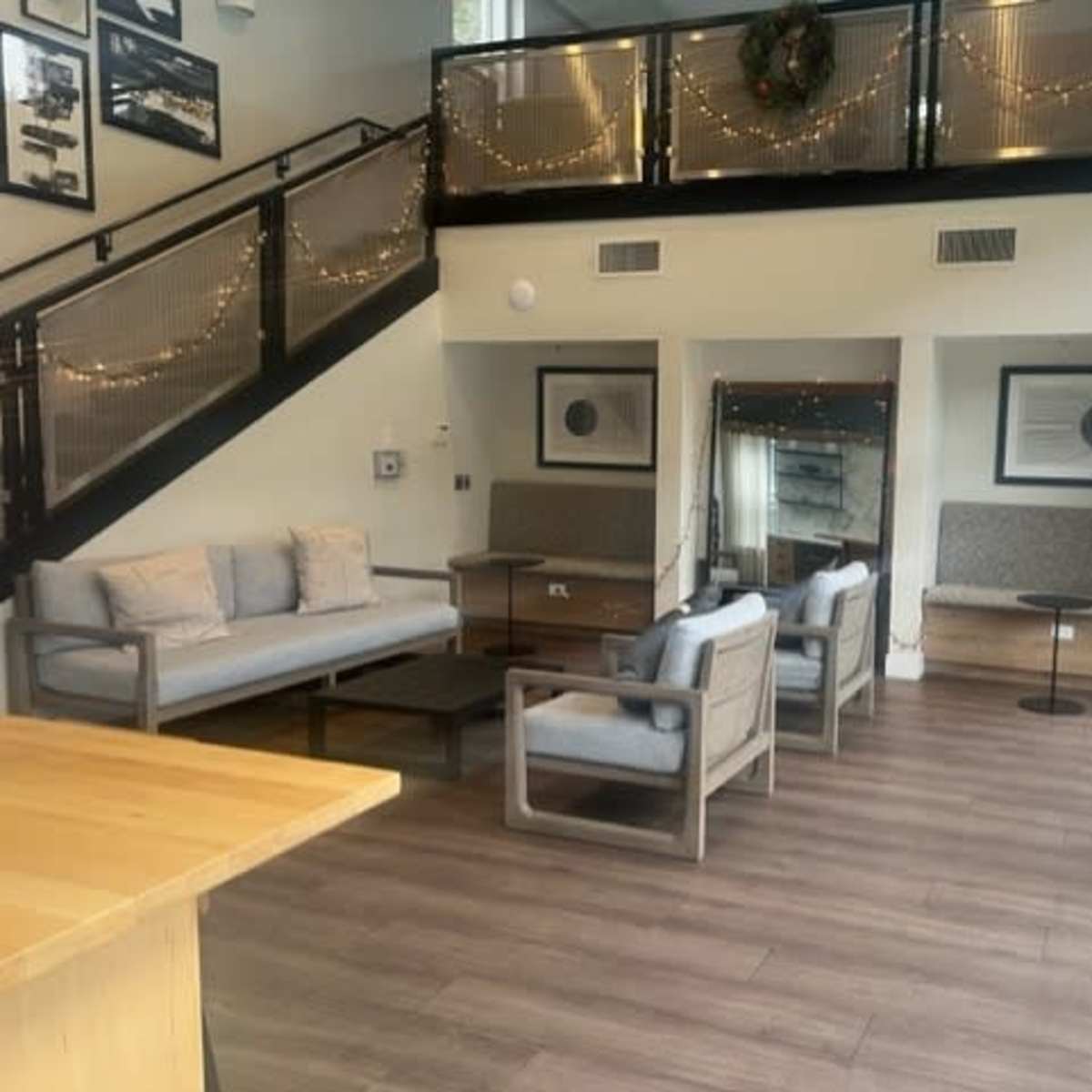 A modern lounge area with several seating arrangements, including couches and chairs, along with decorative wall art and string lights.