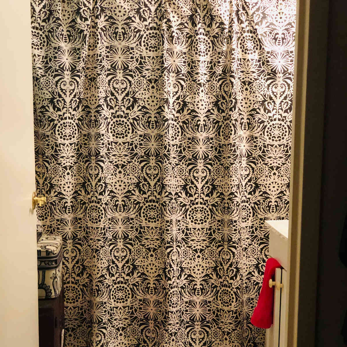 A bathroom with a decorative shower curtain, a toilet, and patterned tile flooring.