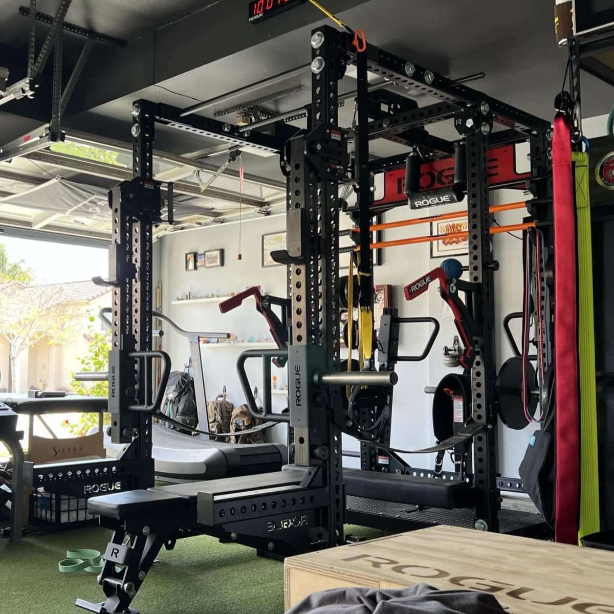 A well-equipped home gym in a garage, featuring various exercise machines, weights, and exercise accessories arranged neatly.