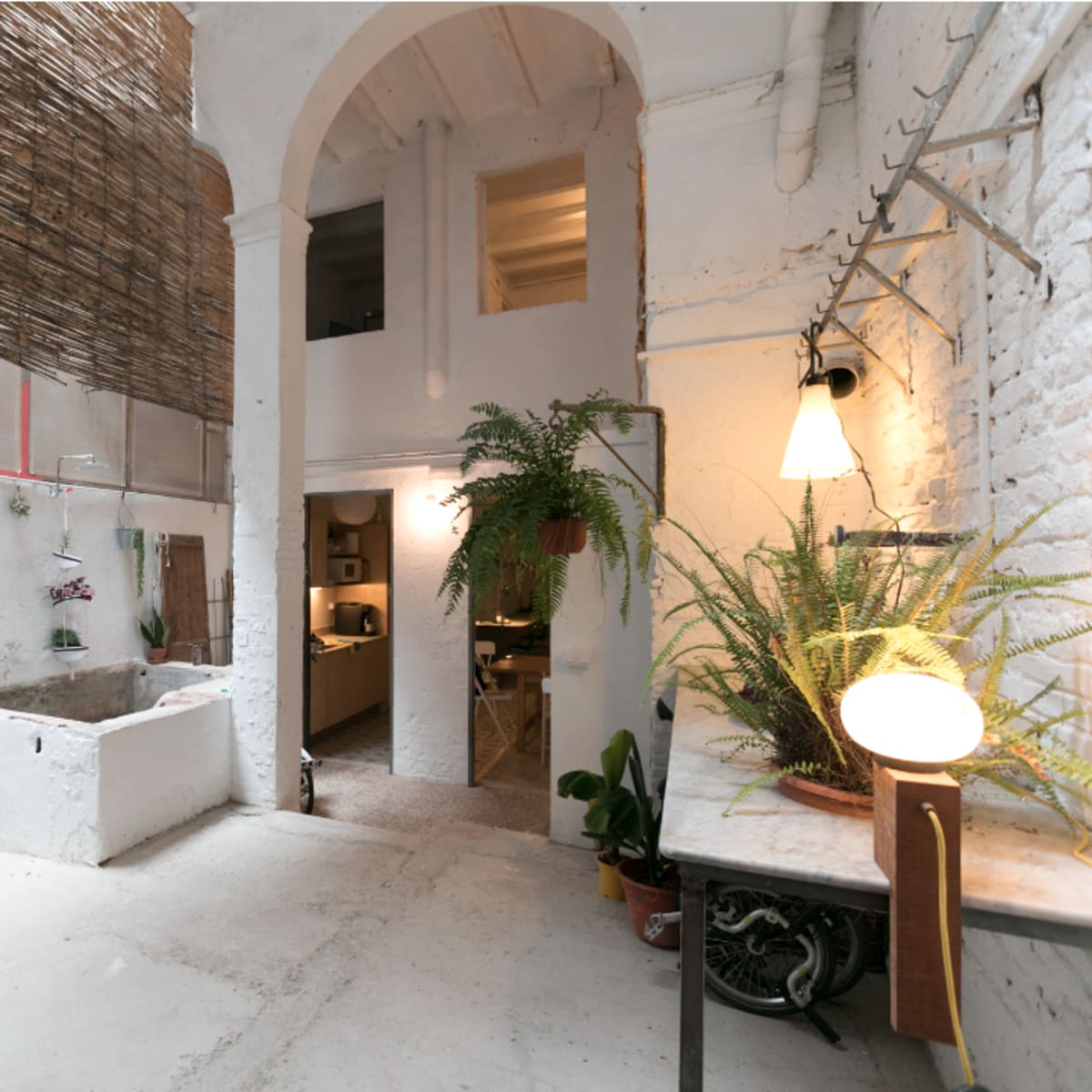 An indoor courtyard with plants, a wash basin, and a partially open ceiling featuring a bamboo covering.
