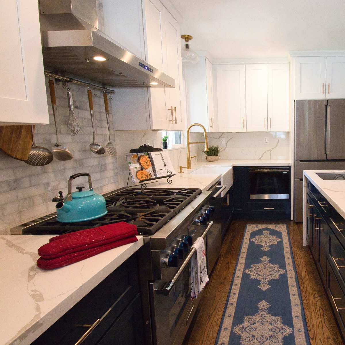 A modern kitchen features white cabinetry, a large gas stove, and a central island topped with marble countertops.